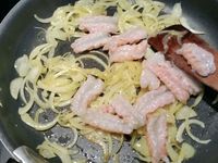 4 - Faire suer et blondir l'oignon émincé dans une poêle avec un filet d'huile d'olive, il doit devenir translucide. Y incorporer les langoustines puis l'estragon haché, saler, poivrer et laisser revenir à feu vif quelques minutes le temps que les langoustines prennent une belle couleur orangée. Faire chauffer la vodka dans une casserole, quand elle frémit la faire flamber et la verser immédiatement sur les langoustines. Disposer une couche d'oignons/estragon sur une belle assiette, déposer dessus 4 langoustines, napper délicatement avec un peu de bisque, saupoudrer votre plat de piment doux ou d'Espelette.