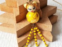 La petite kokeshi prénommée Hikari est montée sur un collier en cordon de coton écru de 56 cm de tour de cou. La poupée mesure 2.5 cm et est agrémentée de perles de rocaille jaune et dorée