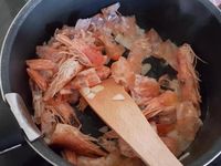 2 - Faire cuire les gambas dans une casserole d'eau bouillante. Les décortiquer en conservant les carcasses et les têtes pour réaliser un fumet, inciser le dos des gambas pour ôter le boyau central. Peler et émincer les oignons. Faire revenir dans une casserole avec un fond d'huile d'olive (2 cuil.) la moitié des oignons émincés. Rajouter les têtes et carcasses de gambas, les écraser un peu avec une spatule en bois pour faire ressortir les sucs, saler, poivrer, recouvrir d'eau à hauteur et laisser réduire sur feu doux 10 à 15 mn. Pendant ce temps, peler et dégermer l'ail et l'échalote et les émincer.