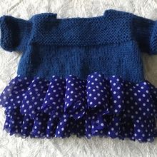 Une nouvelle robe poupée tricotée avec du ruban