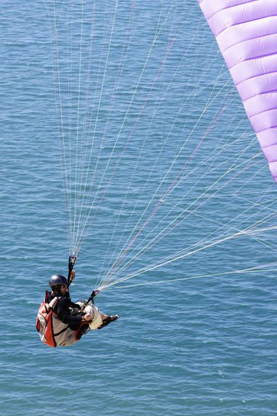 Parapente à la Dune de Pyle, Pyla-sur-mer, Arcachon. Des ailes de toutes les couleurs dans le ciel bleu, sur fond de mer et de sable.