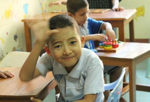 Enfant handicapé de l'Eden Center en Birmanie, signant un au revoir. 