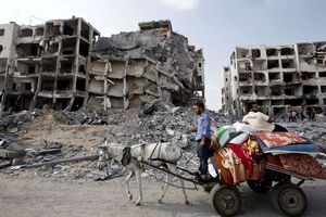 Gaza Under Attack : Palestinian men ride a donkey cart past destroyed buildings in the northern Gaza Strip