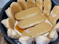 3 - Peler à vif les mandarines restantes. Tremper très rapidement les biscuits dans le fond de rhum ou de fleur d'oranger. Les disposer dans un moule à charlotte sur les bords et dans le fond. Verser une couche de crème, puis répartir des quartiers de mandarines et poser une nouvelle couche de biscuits. Renouveler l'opération jusqu'à terminer par une couche de biscuits. Réserver au réfrigérateur pendant 12h minimum.  