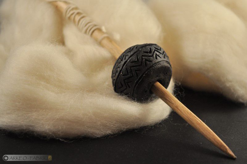 Fusaïole et fuseau de laine filée, d'inspiration âge du Fer. 