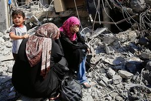 Palestinian women sit on the rubble of their home in Beit Hanoun, Gaza Strip