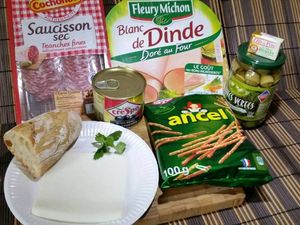 1 - Découper le bout d'une baguette posée à plat en 2 morceaux. Poser un seul morceau de pain sur la tranche de fromage pour la découper à la même dimension avec un couteau. Beurrer une rondelle de saucisson et la recouvrir d'une deuxième.