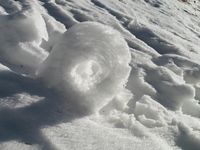 Des jeux de lumière au col. La neige a roulé le long de la pente formant une roue.