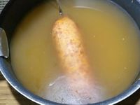 1 - Mettre le four à préchauffer th 6 (180°). Laver le chou dans une grande quantité d'eau vinaigrée, rincer et égoutter. L'émincer en julienne et mettre à pocher pour 3 mn environ dans une casserole d'eau bouillante. Egoutter et réserver. Dérouler la pâte feuilletée, la découper en un disque de 18 cm environ à l'aide d'un cercle. La placer sur une plaque allant au four, badigeonner avec le j'aune d'oeuf, recouvrir d'une feuille de papier sulfurisé, d'une deuxième plaque et enfourner pour 10 mn environ th 6 (180°). Pendant que votre pâte cuit, préparer votre fond de veau, y plonger la saucisse à froid, porter à ébullition et laisser cuire pendant 20 mn.