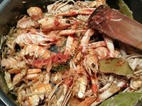 2 - Garder les têtes et les pattes des langoustines pour réaliser une bisque. Peler les échalotes et les gousses d'ail et les dégermer. Dans une casserole faire revenir dans un filet d'huile d'olive les carcasses de langoustines. Bien les écraser avec une spatule en bois pour faire ressortir le jus et permettre aux arômes de se libérer, laisser cuire 10 mn en remuant. Ajouter ensuite les échalotes, l'ail, le bouquet garni, laisser cuire 3 mn jusqu'à coloration. Incorporer ensuite la purée de tomates, et le concentré de tomates, mélanger et laisser fondre 2 mn. Couvrir enfin d'eau à hauteur, et laisser mijoter pendant 30 à 40 mn à feu doux.