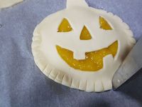 3 - Garnir les 2 disques pleins des têtes de citrouille avec la compote de mangue et l'une des petites rosaces. Recouvrir avec les têtes de citrouille évidées en soudant bien les bords avec un peu d'eau, faire de même avec la rosace. Décorer les bords avec un couteau comme sur la photo.  Dorer le tout au pinceau avec le jaune d'oeuf délayé dans un peu d'eau. Enfourner th 6 (180°) pour 15 mn environ en surveillant. La pâte doit être gonflée et dorée. Laisser refroidir et servir tiède ou froid en dessert gourmand à vos petits amateurs d'Halloween.