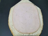 1 - Découper la tranche de pain comme sur la photo, la tartiner de mayonnaise (ou de ketchup, ou autre sauce suivant les goûts).  Y déposer une tranche entière de blanc de poulet en découpant la base pour qu'elle soit bien droite. Détailler 4 disques à l'emporte-pièce rond dans la tranche de fromage de chèvre. Recouper au 1/3 comme sur la photo.