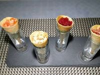 1 - Réaliser les cônes en feuilles de Brick comme expliqué sur la vidéo. Les garnir ensuite d'une mousse d'avocat à la crème fraîche assaisonnée de sel et de poivre, et des ingrédients de votre choix, ici : petits dés de tomate ou de betterave, crevettes grises, bâtonnets de jambon de Parme, le tout parsemé de quelques graines de sésame et de piment d'Espelette. Servir en amuse-bouche à l'apéritif !  