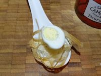3 - Disposer un peu de crème dans le fond de cuillères ou mini-ramequins à apéritif, puis déposer délicatement les nids de brick, placer sur le nid une moitié d'oeuf de caille, ajouter un peu de fleur de sel, du paprika, quelques graines de sésame et décorer d'un brin de persil plat.