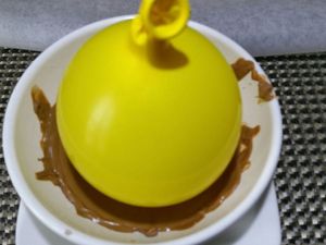 2 - Faire fondre le chocolat avec précaution au micro-ondes dans un bol. Laisser légèrement tiédir. Gonfler un ballon à la taille voulue et en tremper la base délicatement dans le bol de chocolat. Poser un petit disque de chocolat sur du papier sulfurisé et poser la base du ballon enrobé de chocolat sur ce petit disque. Laisser refroidir complètement. Décoller délicatement la coupelle du papier sulfurisé avec un couteau. Puis appuyer doucement sur le ballon sur tout le tour de la coupelle pour dégager le chocolat. Faire ensuite une légère entaille dans le haut du ballon (près du noeud) pour qu'il se dégonfle lentement. Votre coupelle est prête à être garnie.