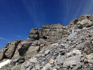 Le long d'une zone de débris, on passe à droite de cette construction ronde et blanche, sous le gendarme avec la croix, puis on descend les dalles lisses et le pierrier jusqu'au sentier pédestre à 2400m.