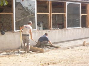 Vendredi 19 septembre 2014 : début des travaux.  Les maçons ont fait une tranchée avec la mini-pelle. Ils ont coulé du béton avec le camion toupie.  Un camion a amené des parpaings. Ils ont mis des parpaings dans la tranchée et fait deux murs à l'intérieur.  Ils ont coulé du ciment devant. Le maçon a étalé avec la règle et a lissé.