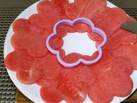1 - Coupez la pastèque en disques assez fins. Réalisez dans les tranches de pastèque des découpes en forme de fleurs à l'aide d'une emporte-pièces (2 par personne). Coupez et retirez les pépins du melon, détaillez-le en tranches pour pouvoir réaliser des petits disques avec un emporte-pièces rond. Lavez, équeutez et coupez les fraises en fines lamelles dans la hauteur.  