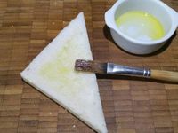 2 - Frotter les tranches de pain de mie avec l'ail. Les couper en diagonale pour obtenir des triangles, et les badigeonner au pinceau avec de l'huile d'olive (ou du beurre fondu).Disposer les tranches de pain de mie sur une plaque allant au four recouverte de papier sulfurisé, parsemer un peu de piment d'Espelette et passer au grill du four pendant quelques instants pour les dorer. Pendant ce temps battre les 4 oeufs en omelette, saler et poivrer légèrement.