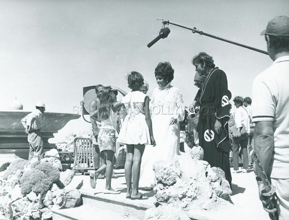 1967, Sardinia - On the set of "Boom" from Joseph Losey - Liza Todd and Elizabeth's niece Dorothy Taylor come to see her and Richard Burton on the stage. Elizabeth Taylor and Liza Todd are on the lap of Richard Burton, together with Dorothy Taylor.