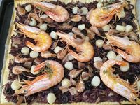 2 - Répartir les oignons en une couche régulière sur la pâte, poivrer et saler très légèrement, rajouter les rondelles d'olives puis le thym lavé séché et émietté. Poser vos anchois sur du papier absorbant pour retirer l'excédent d'huile. En réserver un entier pour la décoration et couper les autres en petits morceaux à répartir sur la pissaladière. Enfourner la pissaladière pour 20 mn environ en surveillant (th 6), puis la sortir et disposer le reste des ingrédients : noix de pétoncles, crevettes grises, gambas et enfourner à nouveau pour 5 mn. Servir aussitôt entière à partager ou découper des portions individuelles à présenter au plat