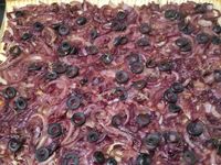 2 - Répartir les oignons en une couche régulière sur la pâte, poivrer et saler très légèrement, rajouter les rondelles d'olives puis le thym lavé séché et émietté. Poser vos anchois sur du papier absorbant pour retirer l'excédent d'huile. En réserver un entier pour la décoration et couper les autres en petits morceaux à répartir sur la pissaladière. Enfourner la pissaladière pour 20 mn environ en surveillant (th 6), puis la sortir et disposer le reste des ingrédients : noix de pétoncles, crevettes grises, gambas et enfourner à nouveau pour 5 mn. Servir aussitôt entière à partager ou découper des portions individuelles à présenter au plat