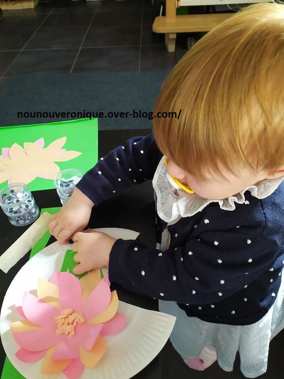Couper une part de l'assiette en carton. Prendre l'emprunte de main de l'enfant sur la feuille verte puis découper. Couper 2 cercles sur la feuille blanche et les coller sur la main verte au niveau du poignet. Laisser l'enfant colle les yeux mobiles sur les cercles blancs. Découper 3 fleurs sur les feuilles roses et les colles en quinconse sur leurs milieu. Coller des morceaux de papier crépon pour faire le coeur de la fleur. Recourber les pétales de la fleurs avec le crayons de bois. Coller la fleur sur le nénupha. Coller la grenouille au dessus de la fleur. Puis laisser l'enfant coller la couronne au dessus des yeux de la grenouille puis dessiner un sourire. Bien sur, vous pouvez laisser l'enfant vous aider à coller les differents éléments. 