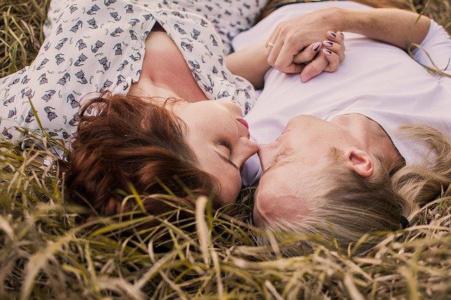 couple allongé sur l’herbe en se tenant la main
