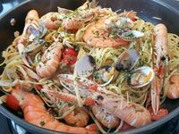 2 - Verser un bon filet d'huile d'olive dans un sauteuse. Faire revenir 1 mn les fruits de mer (langoustines et gambas). Rajouter l'ail (2 gousses), remuer, puis verser le jus de cuisson des coques, mélanger, ajouter les coques et tellines (en garder quelques unes pour la décoration). Rajouter les tomates cerises, les câpres, mélanger et incorporer les linguine en remuant, laisser réchauffer sur le feu 2 à 3 mn. Décorer du reste de coquillages et parsemer de persil haché. Présenter directement dans la sauteuse en rajoutant sur le dessus des pâtes les 4 cuil.à soupe de crème fraîhe, ou en parts individuelles dans des assiettes préalablement chauffées avec 1 cuil.à soupe de crème fraîche par plat. Déguster de suite accompagné éventuellement d'un vin italien.