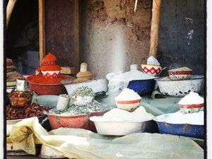 photographie de Soraya Adibord , représentant les marchés dans les peitits villages du désert du Sahara (dans la régions de l'Ennedi  et de Faya situés au nord du Tchad ) .Pour leur survie le commerce est essentiel :vente de bettaille ,dattes,thé,céréales (...) .