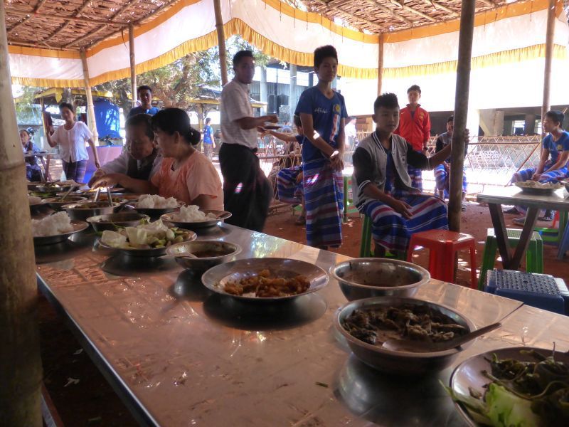 Les cuisines avec les dames au travail épluchant et préparant les légumes puis la table où tous les convives peuvent s'asseoir et déguster