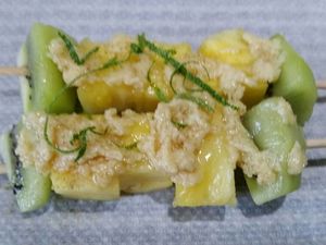 2 - Mettre votre four à préchauffer th 6 (180°). Piquer les morceaux d'ananas et de kiwis sur de longues brochettes en bois. Râper le citron vert bio en zestes. Déposer 2 brochettes sur du papier sulfurisé et les tartiner assez généreusement de beurre de Rhum. Saupoudrer de zestes de citron vert. Rabattre la feuille de papier sulfurisé sur les brochettes et la fermer pour former les papillotes en repliant et agrafant le centre et les bords. Procéder de la même façon pour obtenir 4 papillotes contenant 2 brochettes chacune. Mettre au four pour 15 mn th 6 (180°).
