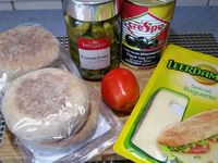 4 - Mettre le four à chauffer en position grill. Emonder et épépiner la tomate. L'écraser à la fourchette pour obtenir une purée, ajouter 1 pincée de sucre pour retirer l'acidité et assaisonner avec du sel. Couper le muffin en 2, le tartiner généreusement de tomate écrasée. Découper de fines bandes dans les tranches de fromage. Les disposer en les croisant (façon bandelettes de momies) sur le haut et le bas du muffin (Cf. photo) en laissant une place libre pour les yeux. Enfourner vos têtes de momie pour 3 à 4 mn sous le grill pour faire fondre le fromage. Pendant ce temps découper 4 rondelles dans les olives noires dénoyautées, remplir le centre d'un morceau de cornichon. Sortir les têtes de momies du four, disposer les yeux dessus.