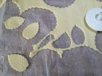 4 - Etaler la pâte feuilletée et y découper à l'emporte-pièce cannelé 12 petits disques et quelques feuilles dans le surplus de pâte avec une empreinte. Disposer au centre de 6 disques un petit tas du mélange poireau/oeuf/olives/pignons. Passer un peu d'eau au pinceau sur les bords et recouvrir avec les 6 autres disques. Bien souder à la fourchette. Décorer d'une feuille de pâte feuilletée.