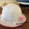 Un petit chapeau estival crocheté en coton blanc agrémenté d'une petite fleur