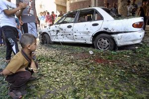 A Palestinian boy looks at a damaged car at the scene of an explosion in Gaza City 