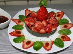 3 - Poser la coupelle sur une jolie assiette à dessert, la remplir des morceaux de fraises découpées. Surmonter d'une fraise entière. Décorer l'assiette de feuilles de menthe, de fraises en lamelles recouvertes de coulis de fruits rouges. Saupoudrer l'ensemble de zestes de Combawa. 