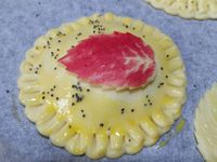 5 - Disposer les petites tourtes sur une plaque allant au four recouverte de papier sulfurisé. Badigeonner à l'oeuf battu, utiliser du colorant alimentaire rouge pour teinter une partie des feuilles. Saupoudrer le tout de graines de pavot. Enfourner th 6,5 (200°) pour 20 à 25 mn en surveillant pour obtenir une pâte bien dorée. Disposer sur une assiette de service et déguster aussitôt.