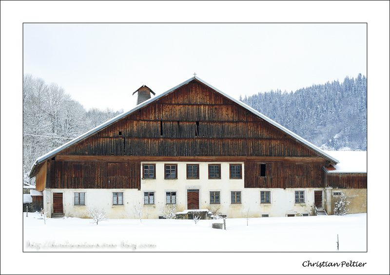 Ferme comtoise et forêt de sapin dans la neige.