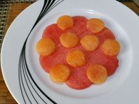 2 - Disposez sur une belle assiette à dessert, une fleur de pastèque, puis les petits disques de melon comme indiqué sur la photo. Recouvrez d'une deuxième fleur de pastèque. Placez les lamelles de fraises en étoile. Décorez le centre de framboises et myrtilles. Placez au réfrigérateur. Au moment de servir, posez une petite meringue sur votre dessert de fruits frais. Emiettez-en une autre sur la fleur étoilée, et parsemez de menthe ciselée et de zestes de combava. 