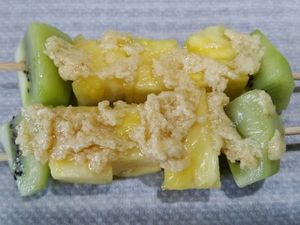 2 - Mettre votre four à préchauffer th 6 (180°). Piquer les morceaux d'ananas et de kiwis sur de longues brochettes en bois. Râper le citron vert bio en zestes. Déposer 2 brochettes sur du papier sulfurisé et les tartiner assez généreusement de beurre de Rhum. Saupoudrer de zestes de citron vert. Rabattre la feuille de papier sulfurisé sur les brochettes et la fermer pour former les papillotes en repliant et agrafant le centre et les bords. Procéder de la même façon pour obtenir 4 papillotes contenant 2 brochettes chacune. Mettre au four pour 15 mn th 6 (180°).