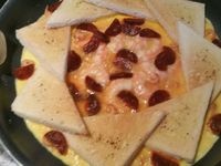 3 - Ressortir du four les tranches de pain de mie dorées. Verser un filet d'huile d'olive dans une poêle, laisser chauffer, puis disposer les triangles de pain de mie en rosace et les faisant se chevaucher. Verser l'omelette au centre de la poêle, laisser prendre quelques instants, puis réduire la puissance sur feu doux (5-6), incorporer les différents ingrédients (crevettes et chorizo) et laisser cuire 5 à 8 mn selon la consistance que vous aimez (baveuse ou non).   