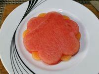 2 - Disposez sur une belle assiette à dessert, une fleur de pastèque, puis les petits disques de melon comme indiqué sur la photo. Recouvrez d'une deuxième fleur de pastèque. Placez les lamelles de fraises en étoile. Décorez le centre de framboises et myrtilles. Placez au réfrigérateur. Au moment de servir, posez une petite meringue sur votre dessert de fruits frais. Emiettez-en une autre sur la fleur étoilée, et parsemez de menthe ciselée et de zestes de combava. 