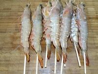1 - Equeuter les champignons de Paris et peler les têtes. Les trancher en fines lamelles, réserver. Peler et hacher finement l'échalote. Prendre des petites piques en bois et embrocher les gambas de façon à ce qu'elles se maintiennent droites à la cuisson (ne pas ôter la carcasse avant d'embrocher les gambas).