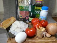 1 - Réunir vos ingrédients. Nettoyer, laver et éponger les calamars. Faire chauffer dans une casserole du lait et le verser bouillant sur la mie de pain émiettée. Bien écraser et malaxer à la fourchette. Peler, hacher l'oignon et l'ail, en réserver une moitié de chaque pour la suite de la recette. Découper le jambon cru en petits morceaux, en garder 2 tranches sans les découper pour la décoration.