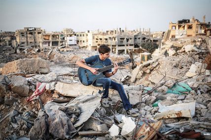 Un jeune palestinien joue de la guitare sur les ruines de sa maison, à Gaza