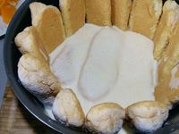 3 - Peler à vif les mandarines restantes. Tremper très rapidement les biscuits dans le fond de rhum ou de fleur d'oranger. Les disposer dans un moule à charlotte sur les bords et dans le fond. Verser une couche de crème, puis répartir des quartiers de mandarines et poser une nouvelle couche de biscuits. Renouveler l'opération jusqu'à terminer par une couche de biscuits. Réserver au réfrigérateur pendant 12h minimum.  