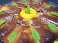 4 - Laisser tiédir pour démouler le gâteau. Couper en tranches fines la 1/2 mangue restante pour décorer le tour et le centre du gâteau. Ajouter quelques feuilles de menthe, de la pralinoise râpée et des points de coulis de fruits rouges.  