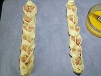2 - Recommencer l'opération avec 3 nouvelles bandes de pâte et une autre saucisse pour réaliser les tresses suivantes de la même façon. Souder bien les bords haut et bas de la pâte. Badigeonner les rondelles de saucisse de moutarde forte. Dorer la pâte au pinceau avec un jaune d'oeuf délayé dans un peu d'eau. Saupoudrer de graines de pavot et mettre à cuire au four th 6 (180°) pour 15 mn à 20 mn environ en surveillant. La pâte doit être gonflée et bien dorée. 