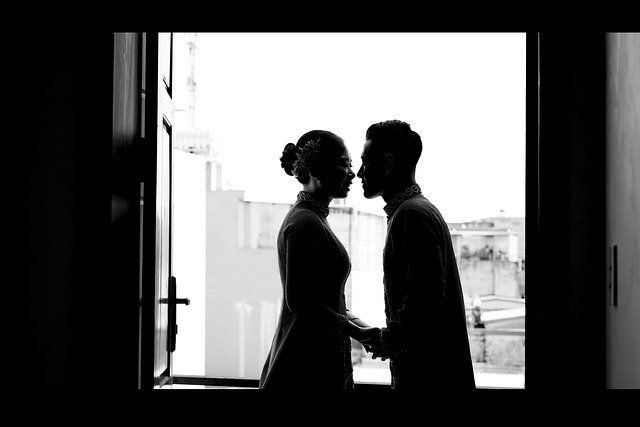 couple se tenant par la main devant une fenêtre